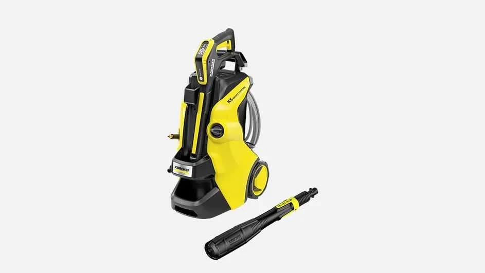 Sur l’image, il y a un nettoyeur haute pression Kärcher K5 jaune avec des accents noirs, une poignée, un enrouleur de tuyau et une lance séparée.