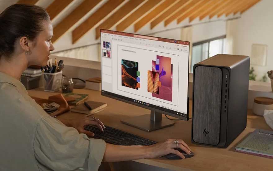 Een vrouw maakt een presentatie op haar desktopcomputer, met kleurrijke afbeeldingen op het scherm en een moderne pc naast haar bureau.