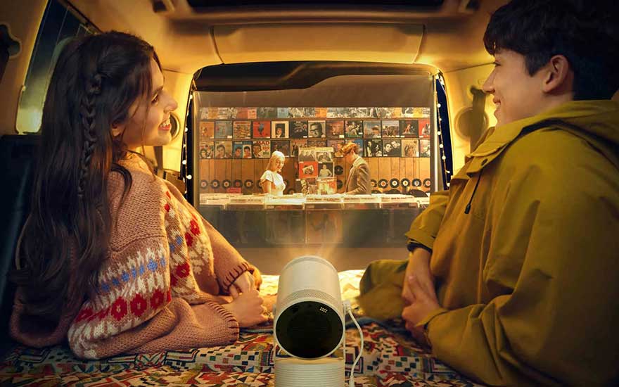 Intérieur de voiture avec projecteur blanc. L'écran affiche une boutique de disques vinyles éclairée. Tapis à motifs colorés.