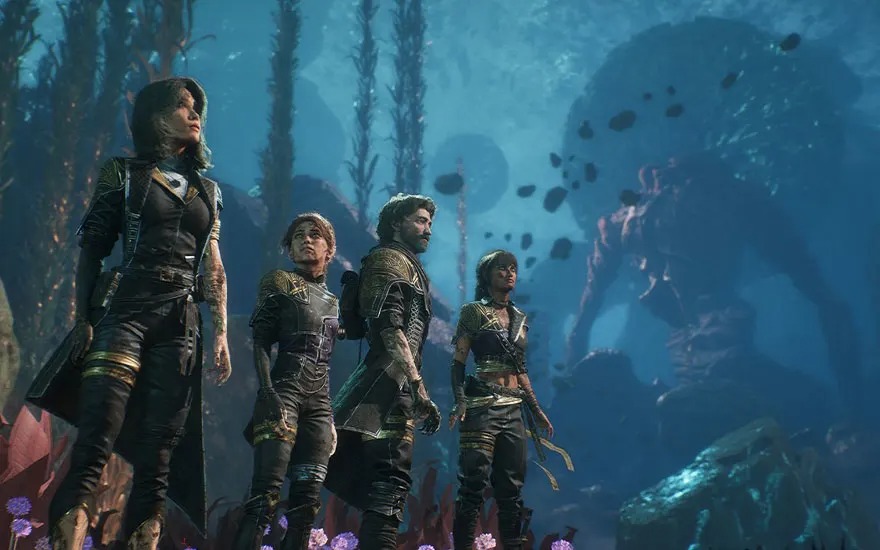 Vier avonturiers in duikpakken staan op de oceaanbodem met een reusachtig monster op de achtergrond. Merk: Avatar: Frontiers of Pandora.