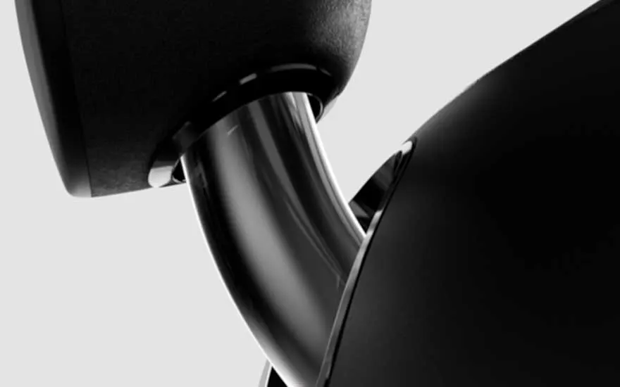 Zwarte speaker met een zilverkleurige, gebogen metalen steun tegen een effen achtergrond.