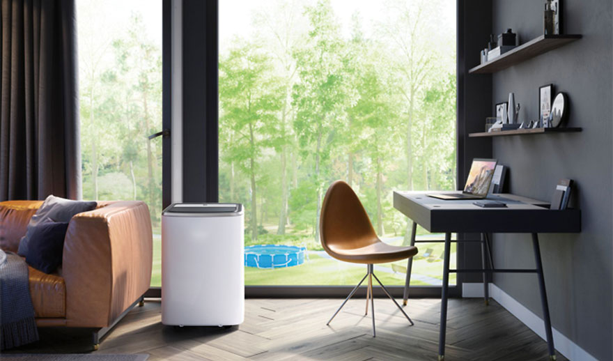 Salon moderne avec canapé cuir, bureau et chaise près d’une grande baie vitrée, un climatiseur mobile blanc est placé.