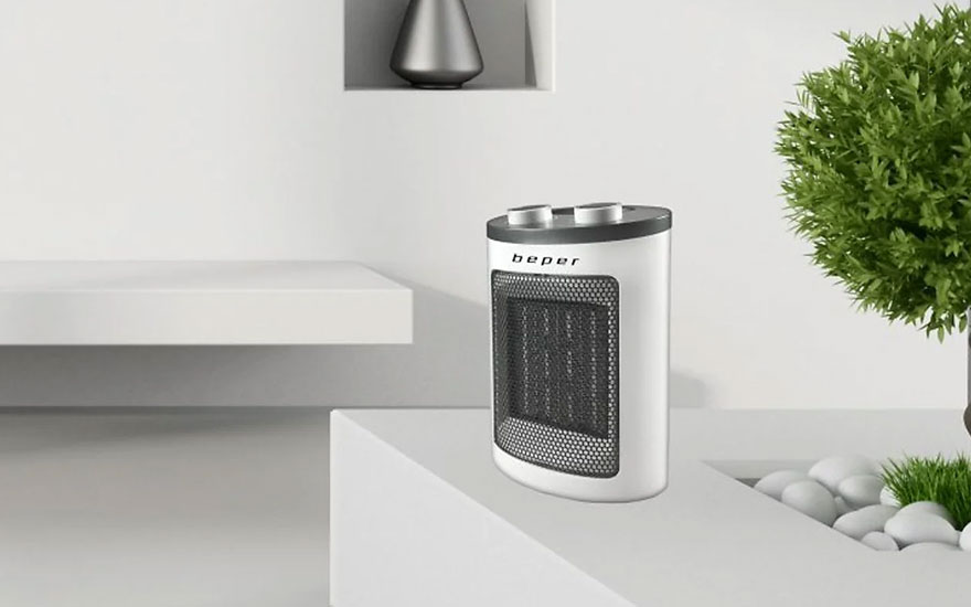 Un radiateur électrique blanc, avec une grille noire, est posé sur une surface blanche. Un arbuste vert est visible en arrière-plan.