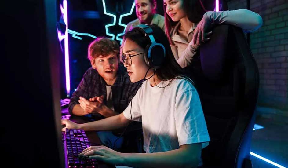 Une pièce éclairée au néon avec un ordinateur, un clavier et des personnes. Des lumières bleues et violettes sont présentes.