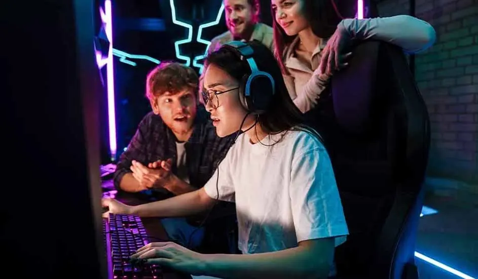 Une pièce éclairée au néon avec un ordinateur, un clavier et des personnes. Des lumières bleues et violettes sont présentes.