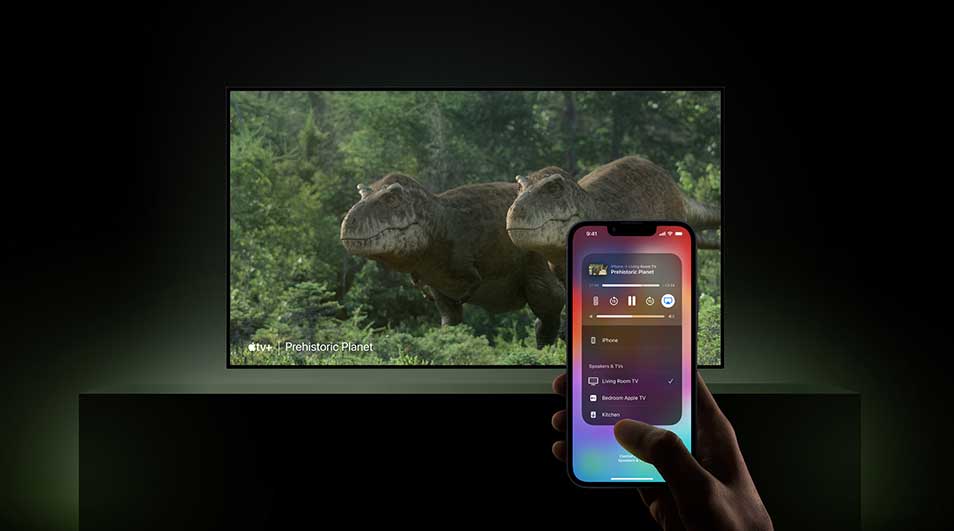 Een tv toont "Prehistoric Planet" met twee dinosaurussen in een groene omgeving. Een smartphone in de hand heeft een afstandsbedieningsinterface.