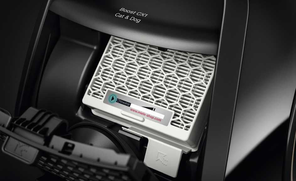 Un filtre blanc avec une grille hexagonale dans un aspirateur noir "Boost CX1 Cat & Dog". Une étiquette est visible.