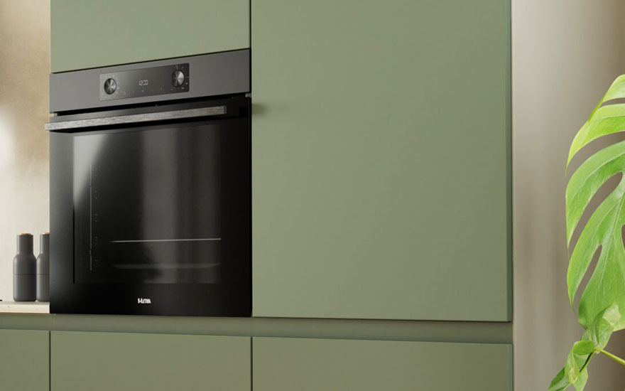 Cuisine moderne avec four noir intégré dans des armoires vert olive. Une plante verte décore le mur beige à droite.