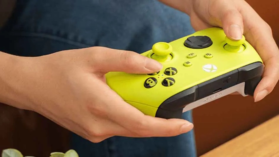 Une personne tient une manette de jeu jaune et noire. Les mains de la personne actionnent les boutons et les joysticks de la manette.