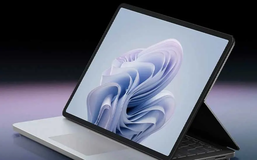 Een zilverkleurige laptop staat open met een blauw abstract patroon op het scherm tegen een donkere achtergrond.