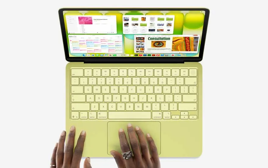 Top view of a yellow laptop with several colourful windows open, as two hands rest on the keyboard against a clean light background.