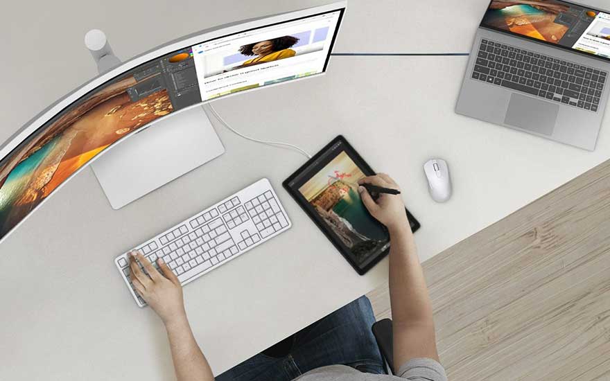 Vue aérienne d'un bureau blanc avec un écran incurvé, un ordinateur portable, une tablette, un clavier et une souris.