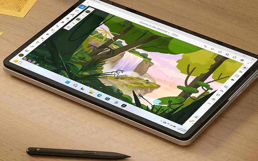 Een tablet ligt op een houten tafel met een zwarte styluspen ernaast. Het scherm toont een tekening van een waterval.
