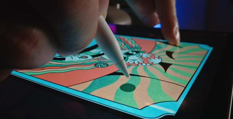 Un stylet numérique dessine sur un écran affichant un motif géométrique orange, vert et bleu. L'écran repose sur une surface noire.