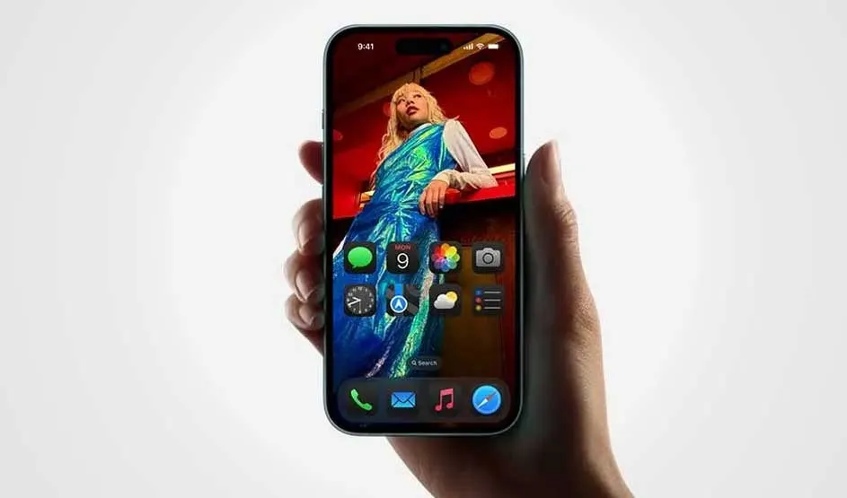 A hand holds an Apple iPhone showing a vivid home screen with large icons over a fashion photo, slim bezels, and the Dynamic Island at the top.