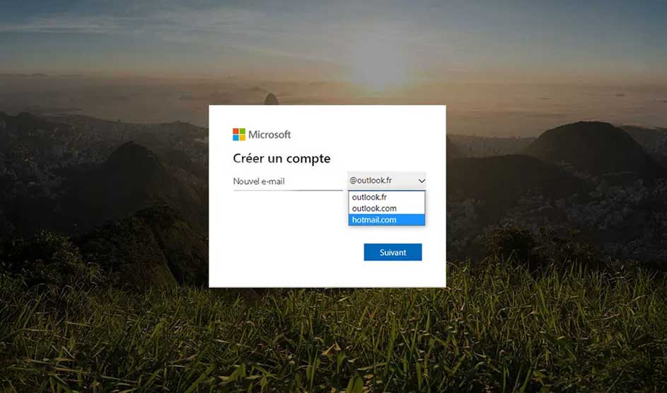 Fenêtre "Créer un compte" Microsoft sur fond de paysage montagneux et herbeux. Options de domaine de courriel visibles.