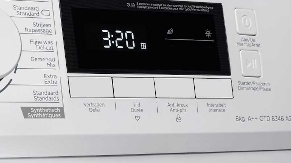 Wasmachinebedieningspaneel. Digitaal display toont "3:20". Knopopschriften in het Nederlands en Frans, functies zoals "Anti-kreuk".
