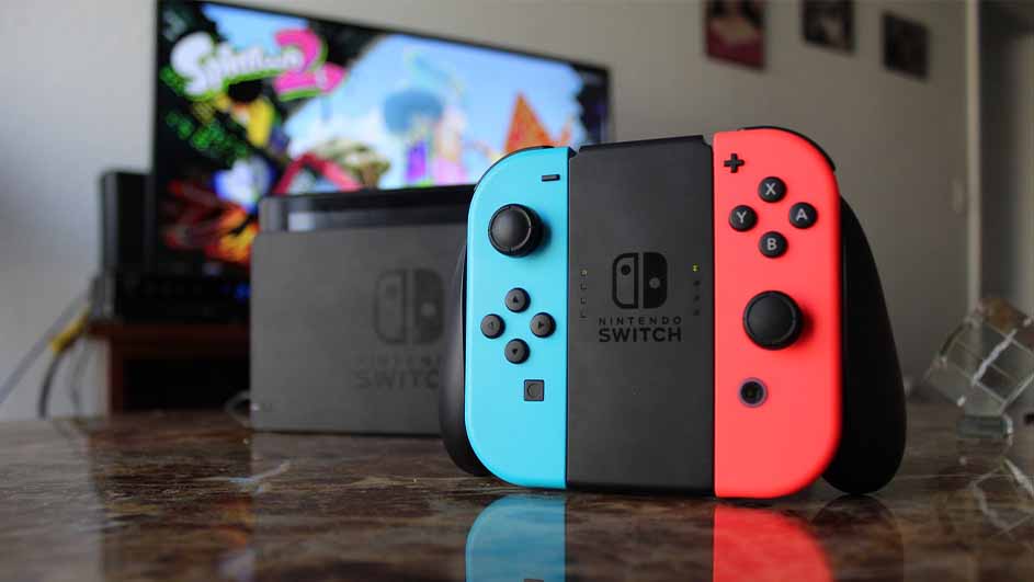 Een Nintendo Switch-console met blauwe en rode Joy-Con staat voor een tv met het spel Splatoon 2, in een woonkamer.