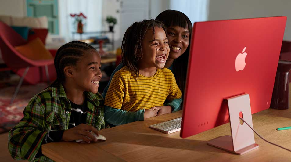 Een rood Apple-computer staat op een houten tafel met een toetsenbord en een muis.