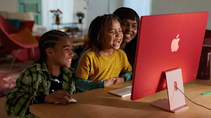 Een rood Apple-computer staat op een houten tafel met een toetsenbord en een muis.