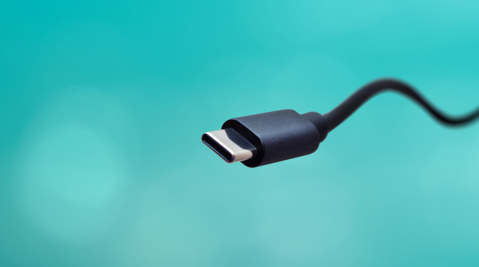 Gros plan d'un connecteur USB-C noir. Le câble est visible sur un fond turquoise uni.