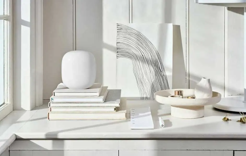 Een witte tafel met boeken, een vaas, een schilderij met lijnen en een schaal met decoratieve items.