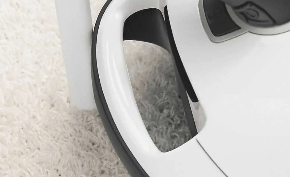 Gros plan d'un aspirateur robot blanc et noir sur un tapis à poils longs blanc cassé.