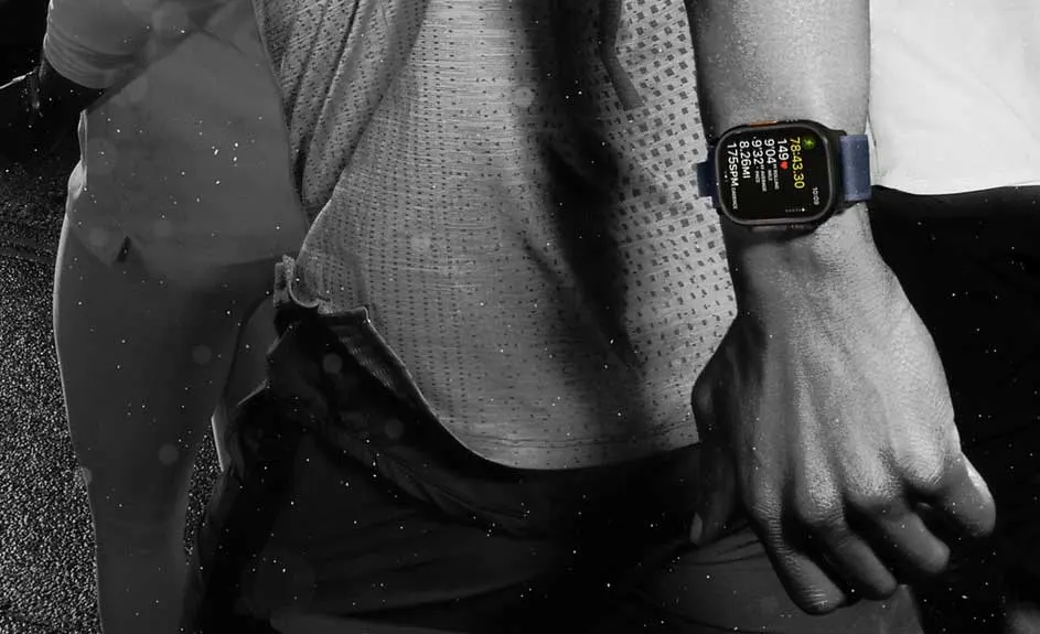 Un gros plan en noir et blanc montre une montre intelligente à écran numérique avec un bracelet bleu au poignet.