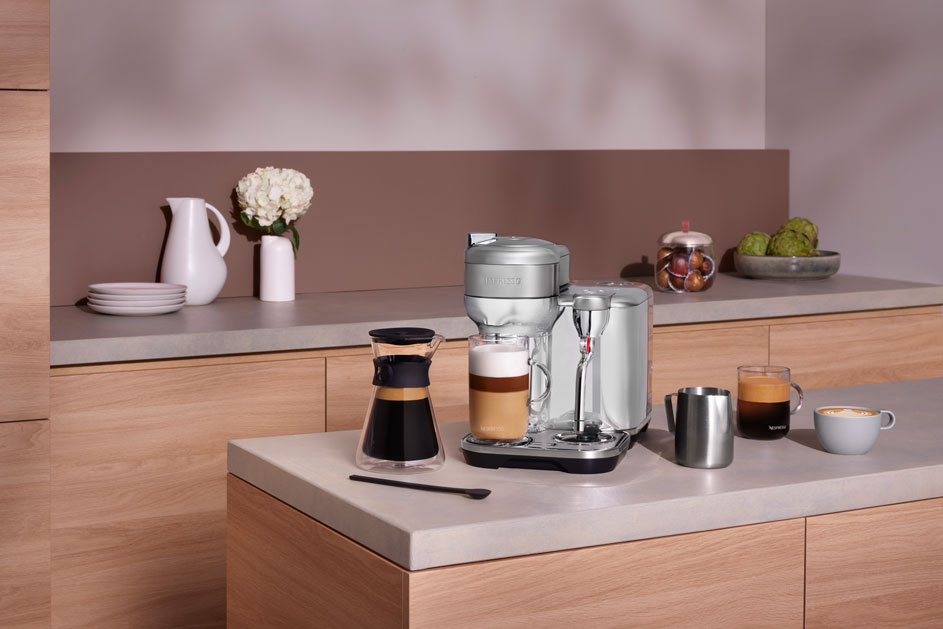 Een keukenopstelling toont een zilveren koffiemachine, koffiekannen en mokken op een aanrechtblad.