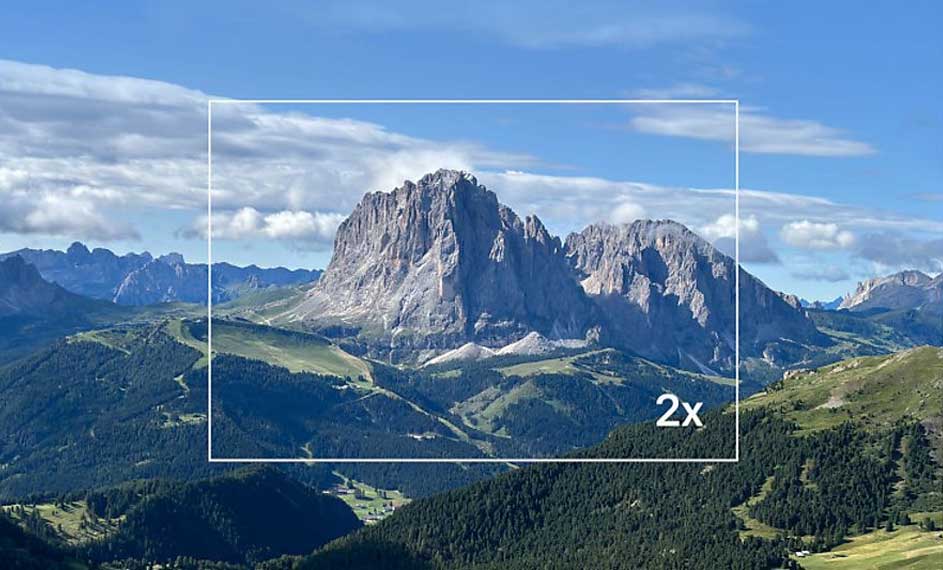 Paysage montagneux avec ciel bleu nuageux. Un rectangle blanc indique un zoom 2x sur une montagne rocheuse au centre.