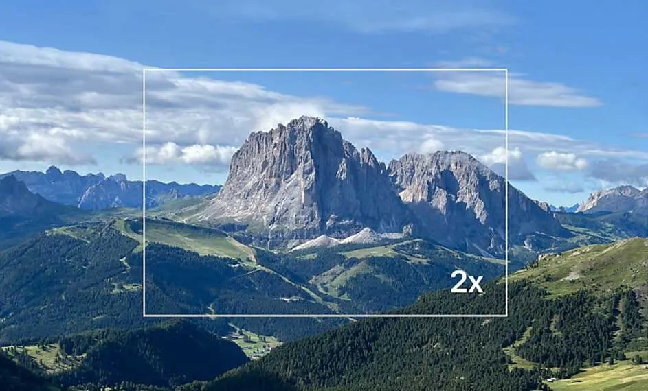 Paysage montagneux avec ciel bleu nuageux. Un rectangle blanc indique un zoom 2x sur une montagne rocheuse au centre.