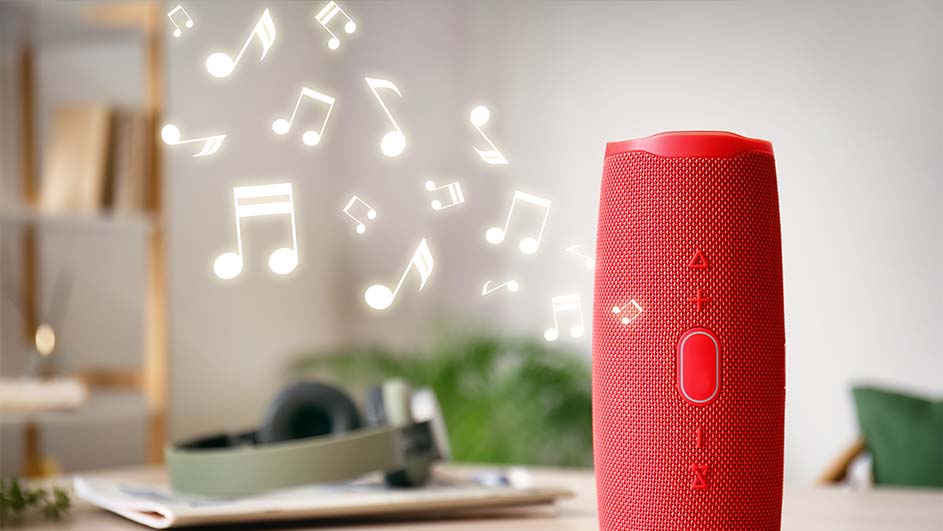Een rode draadloze speaker staat op een tafel met hoofdtelefoon en zwevende muzieknoten op de achtergrond.