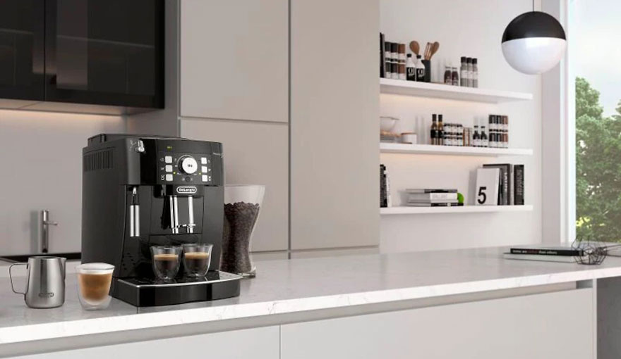 Machine à café noire sur un comptoir blanc avec tasses, pot à lait et grains de café. Étagères et fenêtre en arrière-plan.