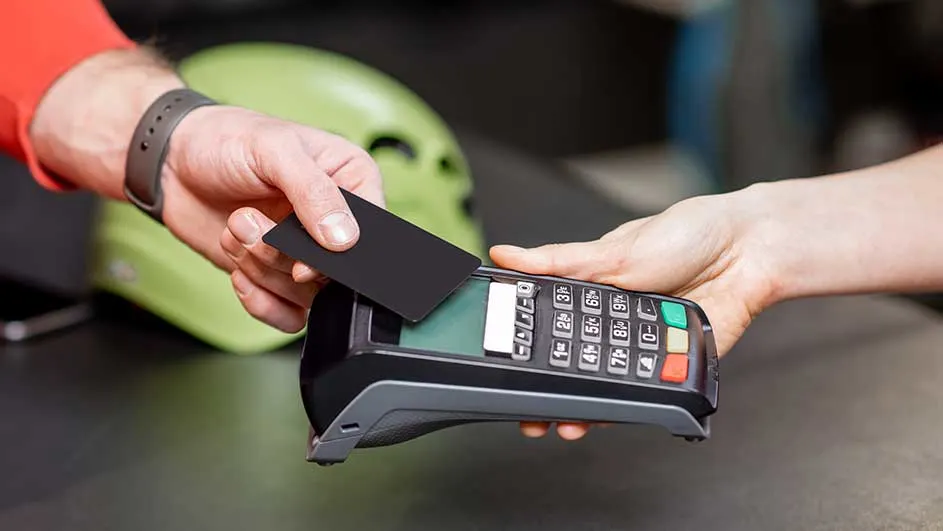 Une carte noire est insérée dans un terminal de paiement noir et gris avec des boutons numériques colorés.