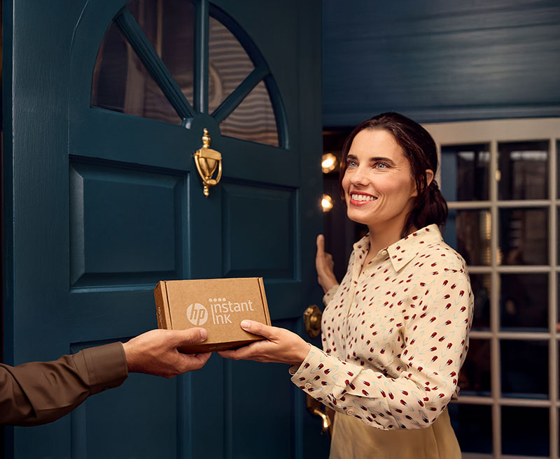 Femme recevant une boîte HP Instant Ink à la porte d’entrée.