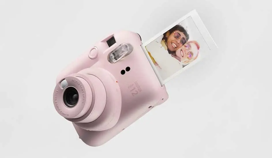 Un appareil photo rose Fujifilm Instax Mini 12 imprime instantanément une photo. Son design est compact et ludique.