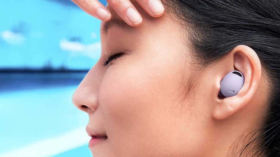 Close-up van een oortje in een oor tegen een achtergrond van blauwe lucht en water. Een hand raakt het voorhoofd aan.