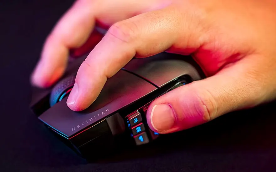 Gros plan d'une main utilisant une souris d'ordinateur noire avec des boutons numérotés éclairés en bleu sur un fond noir.