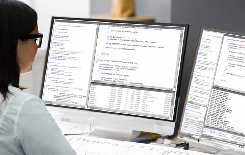 Deux écrans d'ordinateur affichent du code sur un bureau blanc dans un bureau aux couleurs neutres.