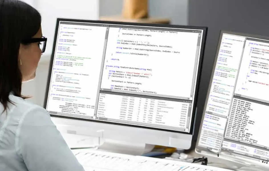 Twee computerschermen tonen code op een wit bureau tegen een grijze achtergrond.