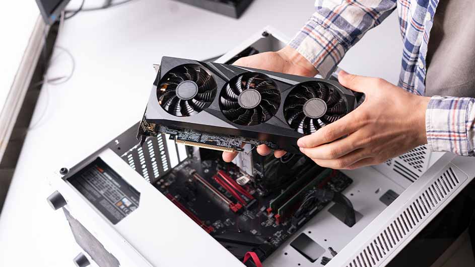 Een grafische kaart met drie ventilatoren wordt boven een computerkast gehouden. De computerkast is wit en zwart.