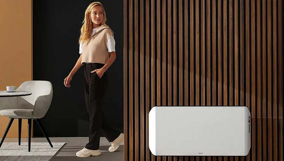 Un mur de lattes en bois verticales côtoie un radiateur blanc rectangulaire. À gauche, une table ronde et une chaise grise.