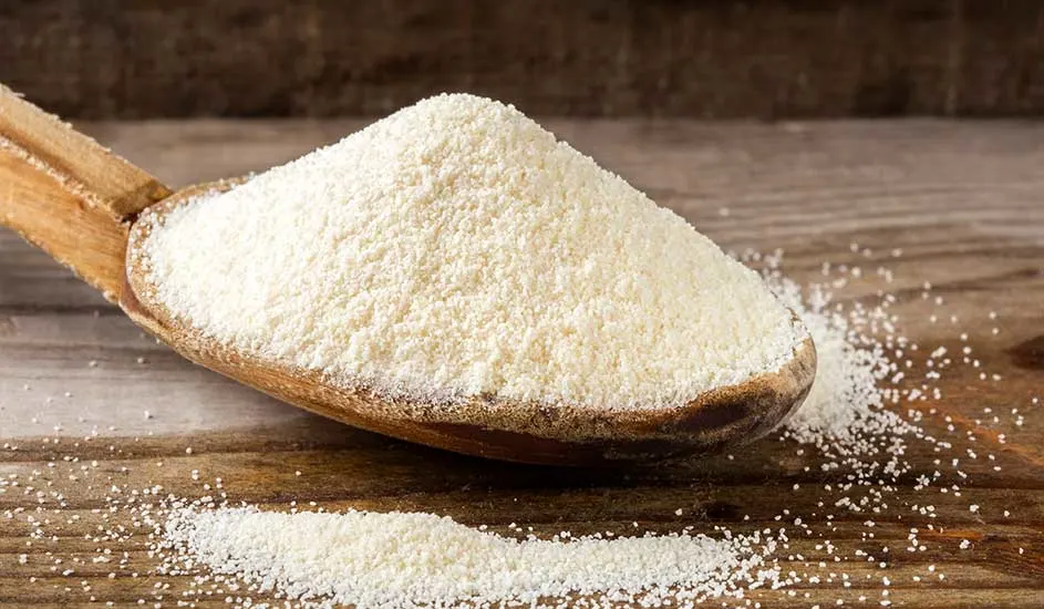 Une cuillère en bois remplie de poudre blanche sur une table en bois rustique.