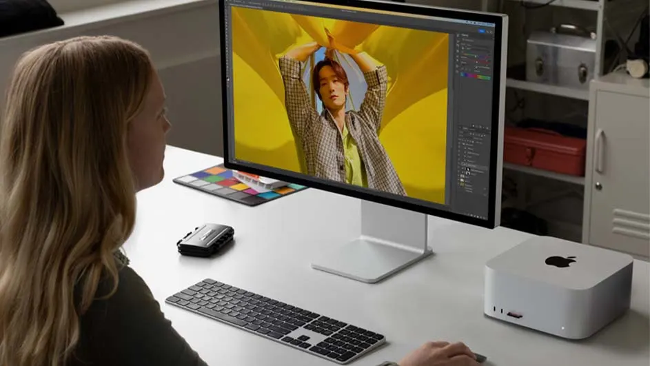 Een bureel met een Apple Studio Display, toetsenbord, muis, en Mac Studio. Op het scherm wordt een foto bewerkt.