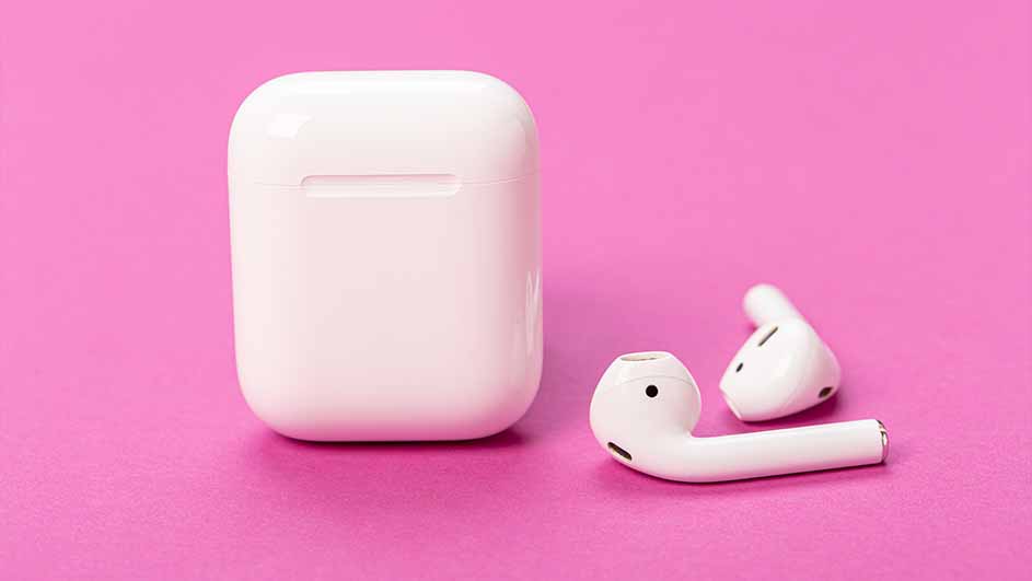 Witte oortelefooncase en twee witte draadloze oortjes op een roze achtergrond.