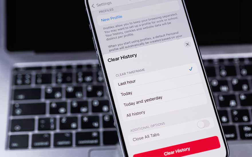Un téléphone affiche les paramètres de confidentialité sur un clavier d'ordinateur portable gris et noir. L'option "Effacer l'historique" est visible.