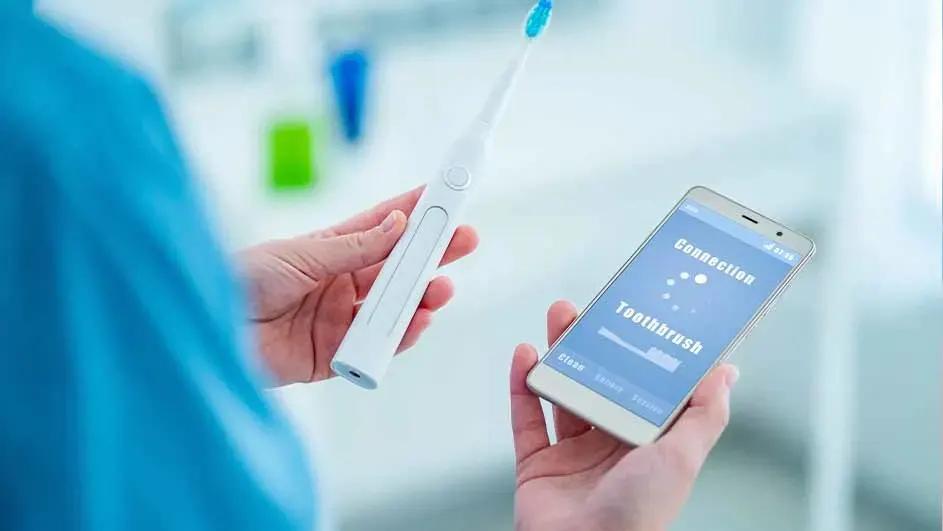 Une personne tient une brosse à dents blanche et un smartphone affichant des données de connexion.