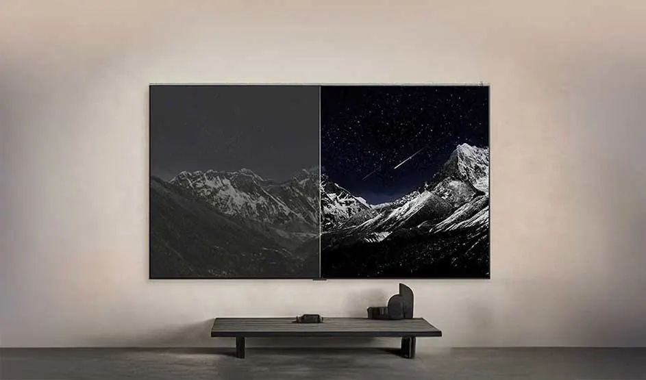 Aan een strakke muur hangt een tweedelig kunstwerk met besneeuwde bergen, links donker en rechts onder een sterrenhemel.