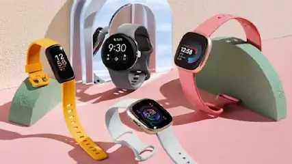 Présentation de montres intelligentes colorées sur des socles vert clair, sur un fond rose pâle.