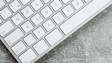 Clavier blanc sur fond gris texturé. Les touches sont carrées avec des lettres noires.